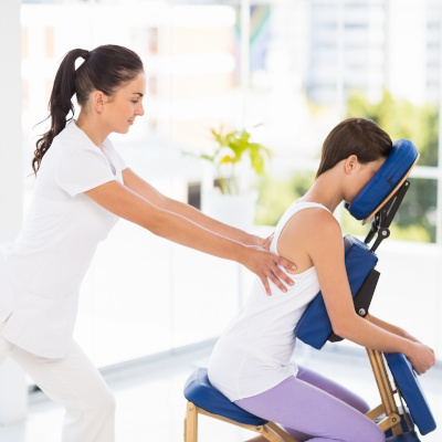 Woman being massaged on chair by masseuse
